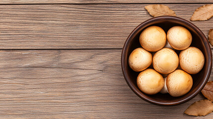Fresh brown mushrooms are piled high inside a rustic bowl placed on a weathered wood surface.