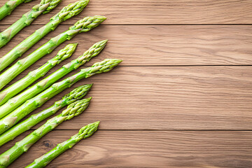 Fresh green asparagus spears are arranged diagonally on a rustic brown wooden surface texture.