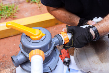 Skilled technician fixes pool filter pump system components while working in backyard