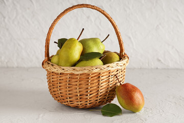 Wicker basket with sweet ripe pears on white background