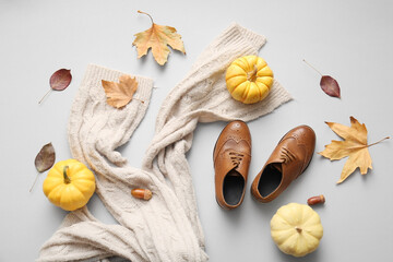 Composition with stylish children's shoes, scarf, pumpkins and fallen leaves on grey background
