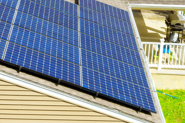 Several solar panels are mounted on sloped roof, capturing sunlight in quiet suburban area.