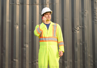 Worker or engineer using walkie talkie and talking about work in containers warehouse storage
