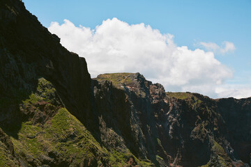 Rugged Cliffs with Green Vegetation Against a Cloudy Blue Sky