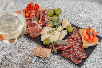 Gourmet charcuterie board with meats prosciutto ham, salami, green olives and cheese with white...