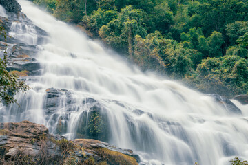 Beautiful waterfall with a lush green forest in the background. The water is flowing down the rocks and creating a beautiful scene. Sustainable waterfall in lush forest promoting water sustainability.