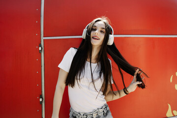 Confident Young Woman in Headphones Against Red Wall