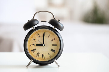 Retro alarm clock on table in bedroom, closeup
