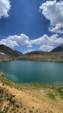 Lulusar Lake in Kaghan Valley, Pakistan, surrounded by lush green hills and a moody, cloud-filled sky. A stunning vertical view, perfect for travel visuals, nature reels, and cinematic landscape use.
