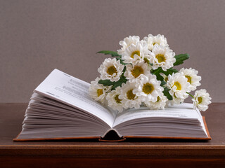 a bouquet of chamomile flowers and old books on a table on a natural background. a composition with books in a rustic style. the concept of reading and relaxing. the summer season. template for regist