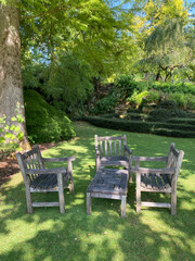 Old wooden garden furniture set placed in a lush garden, evoking rustic charm and outdoor relaxation in a natural setting.