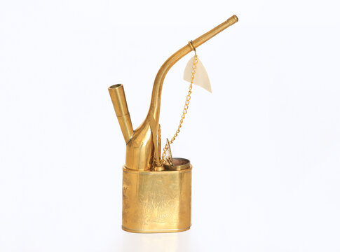 Vintage brass smoking pipe of Asian origin, featuring intricate engravings on the body and a curved mouthpiece. This traditional pipe includes a small attached chain with a decorative element.