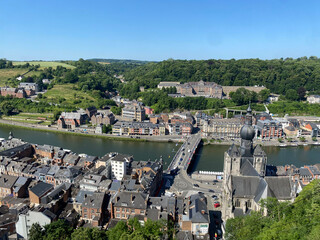 Aerial view of Dinant, Belgium, from the top of the citadel on a clear day, overlooking the Meuse River, cityscape, and surrounding landscape.