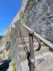 Dramatic perspective view of the steep staircase leading up to the Dinant citadel in Belgium, with stone steps and handrails under daylight.
