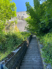 Dramatic perspective view of the steep staircase leading up to the Dinant citadel in Belgium, with stone steps and handrails under daylight.