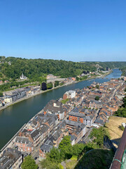 Aerial view of Dinant, Belgium, from the top of the citadel on a clear day, overlooking the Meuse River, cityscape, and surrounding landscape.