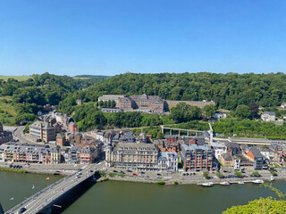 Aerial view of Dinant, Belgium, from the top of the citadel on a clear day, overlooking the Meuse River, cityscape, and surrounding landscape.