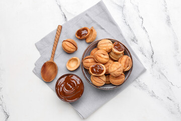 Bowl of sweet walnut shaped cookies with boiled condensed milk on white background