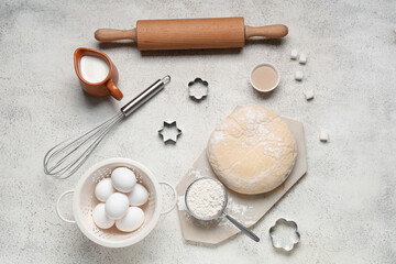 Composition with wooden rolling pin, kitchen utensils, dough and ingredients on grey grunge...