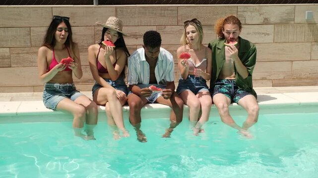 Group of diverse friends enjoying slices of watermelon, sitting on the edge of a swimming pool