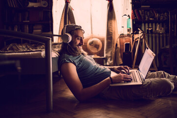 Young man listening to music on his laptop in the living room