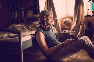 Young man using a laptop while sitting in his bedroom at home