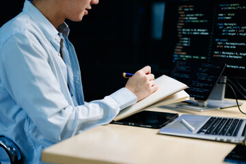 Young male programmer working with tablet and screen displaying code. Modern tech office setup, great for software