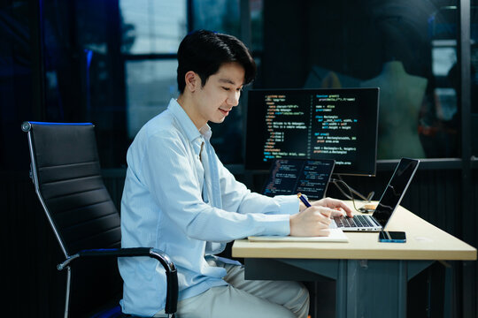 Young male programmer working with tablet and screen displaying code. Modern tech office setup, great for software