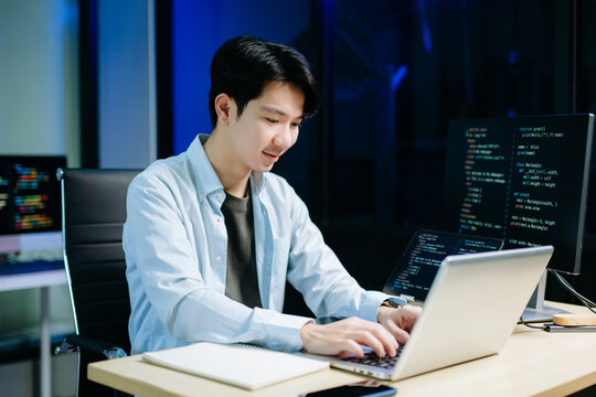 Asian software developer working late with code on screens, tablet, and phone. Concept of programming, tech lifestyle,