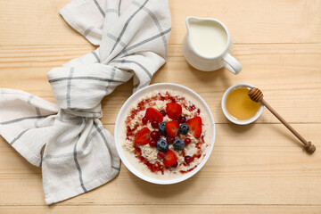 Composition with tasty oatmeal, syrup and berries on wooden background