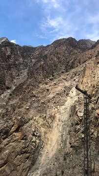 Vertical morning video focused on a rocky mountain. Captured from a down-to-up camera angle, the bare, rugged peak dominates the frame. No greenery or snow, only raw natural rock texture.
