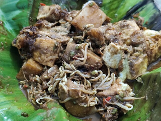 Tahu lontong, a delicious traditional Indonesian dish, lontong with peanut sauce, soy sauce, served with pieces of side dish on banana leaves.