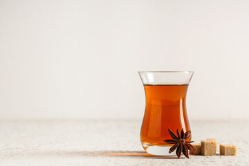 Glass of Turkish tea with sugar cubes and star anise on white background