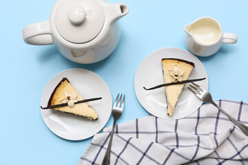 Plates with pieces of sweet vanilla cheesecake and jug of milk on blue background