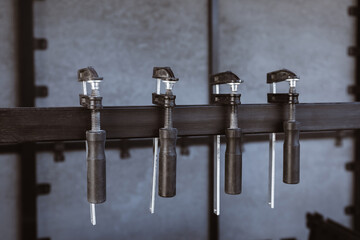 Four black clamps hang on a metal stand against a background of a slate wall on the construction...