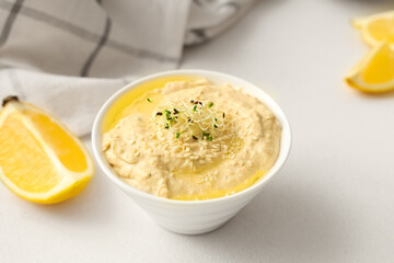 Bowl of delicious hummus with micro green, sesame seeds and lemon on white background