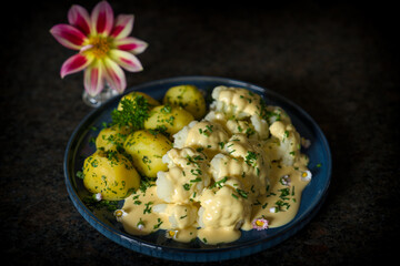 fresh cooking at home and ready to eat - cauliflower, potatoes and hollandaise sauce with herbes from the garden