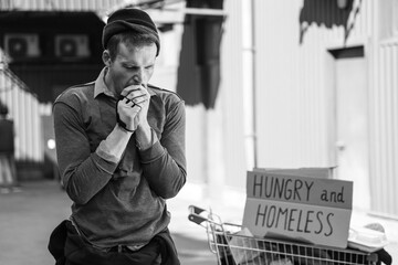 Frozen homeless man warming hands on street