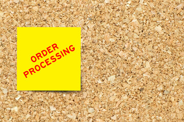 Yellow note paper with word order processing on cork board background with copy space