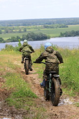 Boys in waterproof clothes and rubber boots ride fatbikes. A fat bike for off-road use