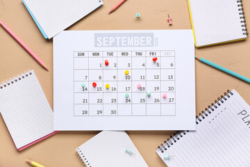 Calendar with notebooks, pencils and pins on beige background. Planning concept