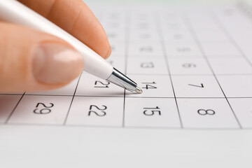 Female hand with pen marking date in calendar, closeup. Planning concept