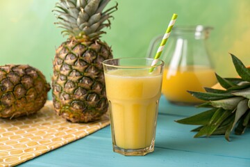 Vivid display of freshly blended pineapple juice showcased in a classy glass with whole and sliced fruit on a stylish blue-wooden backdrop