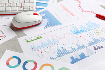 Computer mouse with keyboard, many business graphics and diagrams on grey background