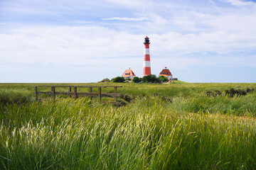 Idyllischer Leuchtturm Westerhever umgeben von grünem Grass unter blauem Himmel