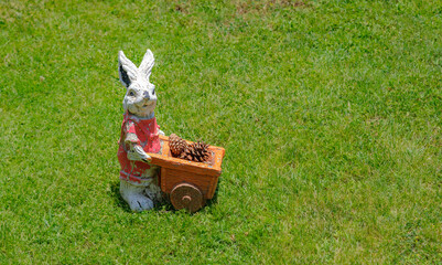Whimsical rabbit garden statue with wheelbarrow. This playful decoration adds a touch of whimsy to a garden. Perfect for themes related to gardening and decor.