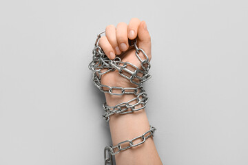 Hand with clenched fist and chains on grey background. Concept of oppression