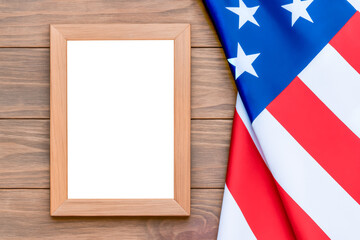 Empty frame with copy space on light wooden table next to American flag for patriotic holidays and congratulations on American Independence Day