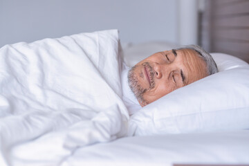 senior man laying comfortable under a white blanket,resting,bedtime deep sleeping in a cozy...