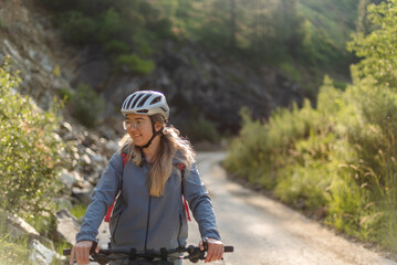 Female cyclist in helmet riding mountain road in sunlight
